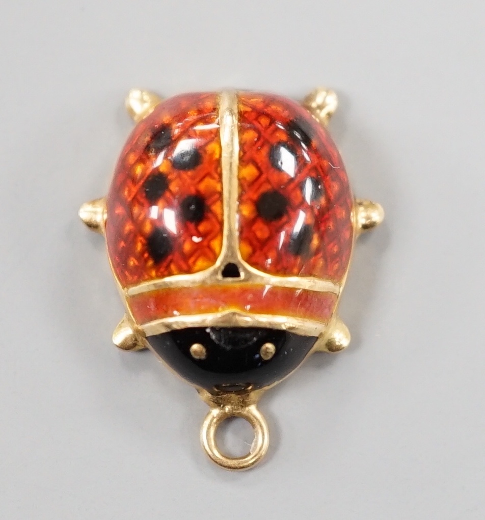 A modern yellow metal and two colour enamel set ladybird pendant, overall 19mm, gross weight 1.7 grams.